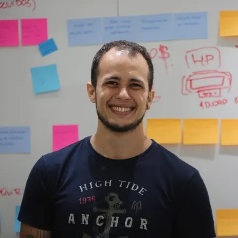 Antônio Augusto em um ambiente de trabalho com anotações ao fundo.