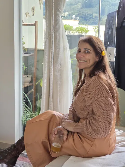 Bia, diarista do Faxinas da Bia, sentada perto de uma janela.